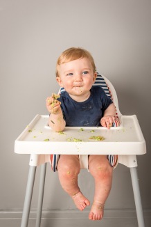 Baby in High Chair eating Veg